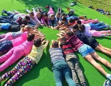 Kinder liegen im Gras im Kreis