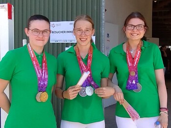 Szenerie: Drei junge Frauen mit ihren bei Reitbewerben gewonnenen Medaillen