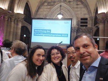 Vier Menschen schauen in die Kamera bei einer Preisverleihung