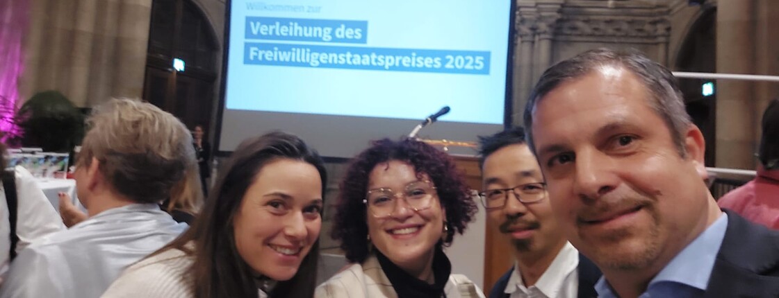 Vier Menschen schauen in die Kamera bei einer Preisverleihung