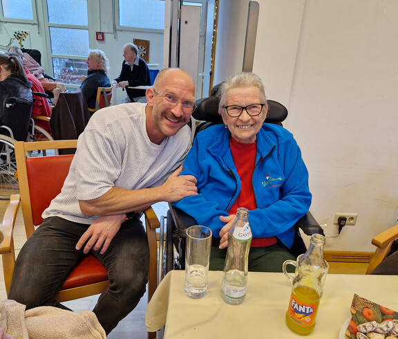 Zwei Personen sitzen eng beisammen am Tisch, Getränke und Weihnachtsdeko sichtbar