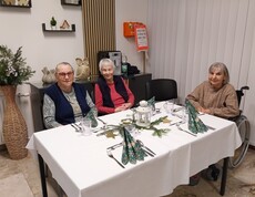 Bewohner*innen sitzen an festlich gedecktem Tisch mit Laterne und weihnachtlicher Deko