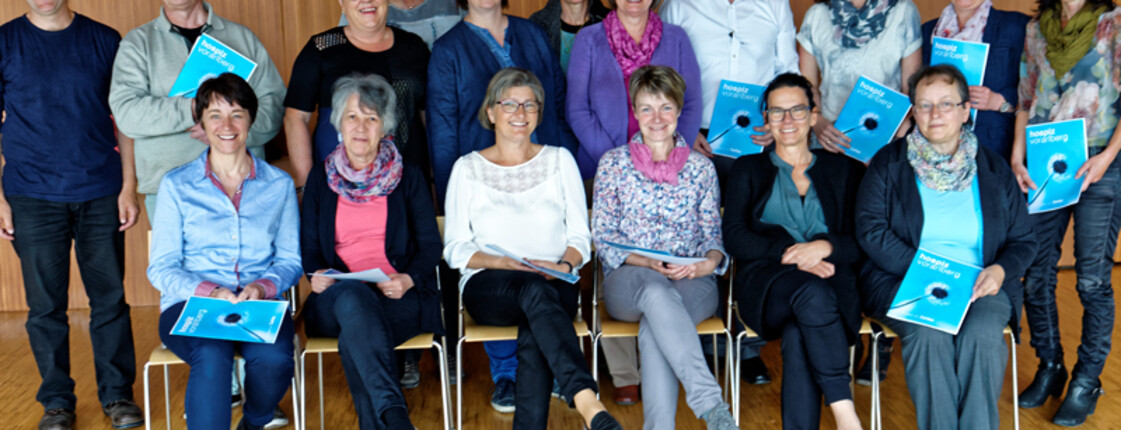 Eine Zertifikatsverleihung von Hospiz Vorarlberg. Sie sitzen und stehen für ein Gruppenfoto zusammen. 