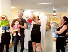 Vier schwarz gekleidete Puppenspieler stehen vor den Bewohner*innen des Caritas Pflegewohnhauses Lannach und führen eine Puppenshow auf. Die Szene zeigt eine lebendige Unterhaltung im Pflegealltag.