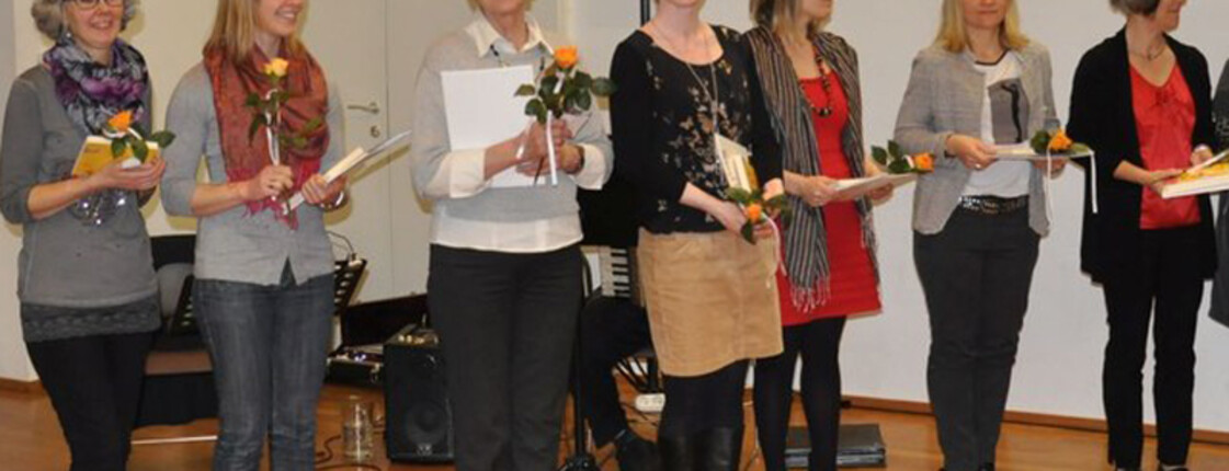 Lesepaten halten eine Rose in der Hand und lachen in die Kamera.