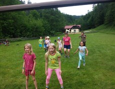 Kinder nehmen auf einer großen Wiese an einem Bewegungsspiel teil und verbringen während der Projektwoche gemeinsam aktive Zeit im Freien.