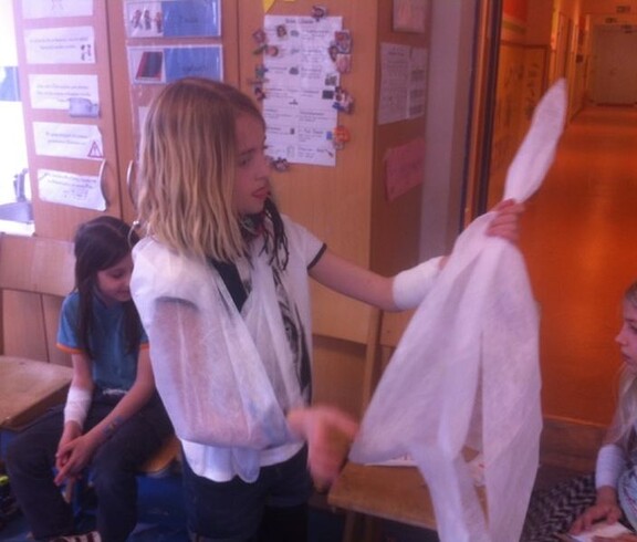 Kinder üben im Rahmen eines Erste-Hilfe-Workshops den Umgang mit Verbänden und Rettungsdecken sowie grundlegende Hilfsmaßnahmen.