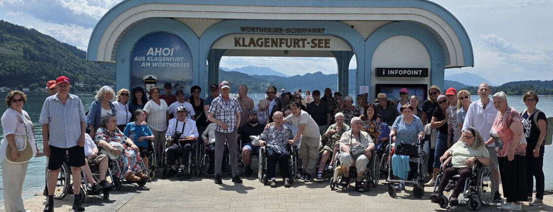 Große Reisegruppe von Haus Klara vor der Schiffsstation Klagenfurt-See am Wörthersee.