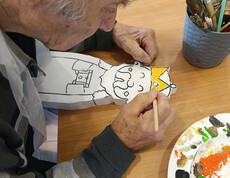 Nahaufnahme einer Hand, die eine Holzfigur der Heiligen Drei Könige bemalt