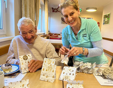 Zwei Personen basteln nummerierte Advents-Säckchen am Tisch