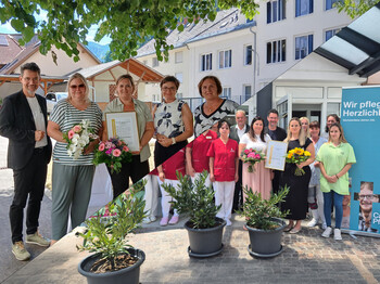 Zwei Gruppen bei EQalin-Zertifikatsverleihung mit Blumen und Urkunden vor Pflegeheimen