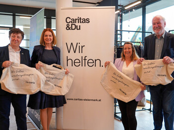 Zur Eröffnung des Carla Hausmannstätten posieren Vizedirektorin der Caritas Petra Prattes, Landesrätin Simone Schmiedtbauer, Abteilungsleiterin Carla & Beschäftigung Tamara Puff und Josef Wilfing, Pfarrer von Hausmannstätten mit einer Tasche