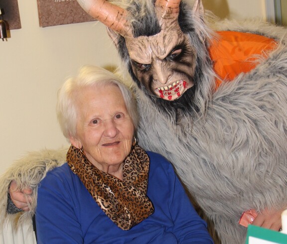 Krampus posiert neben einer Bewohnerin und beide schauen in die Kamera.