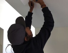 Ein Kind befestigt ein beschriftetes Blatt an der Decke eines Klassenraums und beteiligt sich an der gemeinsamen Gestaltung von Gruppenregeln.