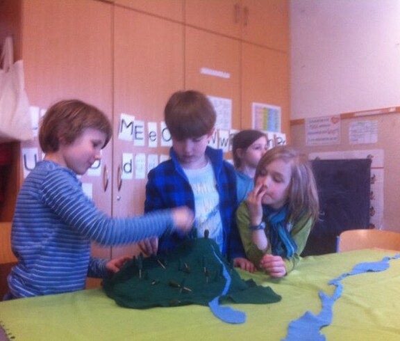 Kinder gestalten gemeinsam ein Landschaftsmodell aus verschiedenen Materialien und erkunden dabei spielerisch natürliche Lebensräume.