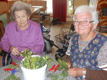 2 Bewohnerinnen binden einen Palmbuschen